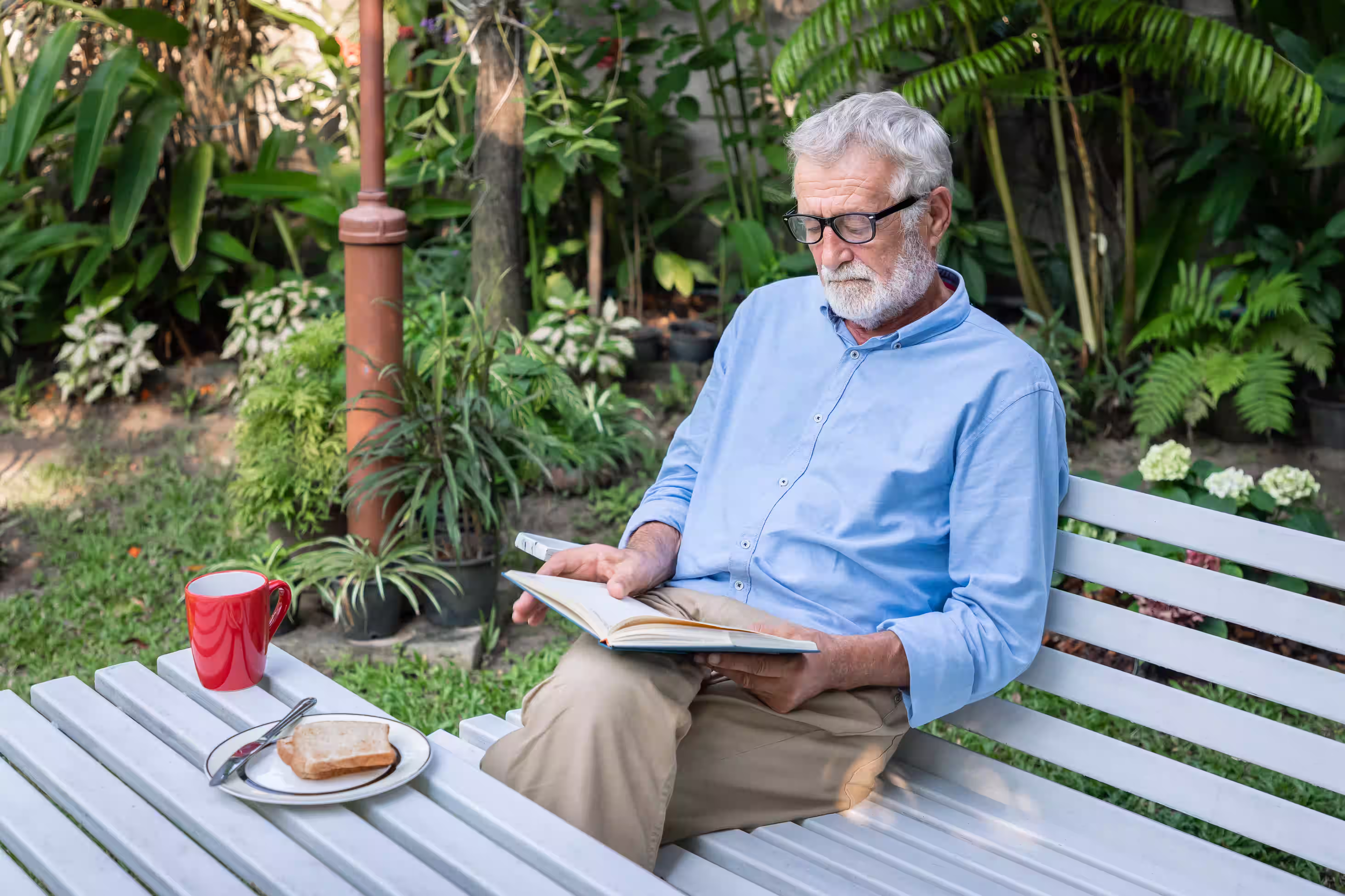 Senior lisant un livre dans son jardin